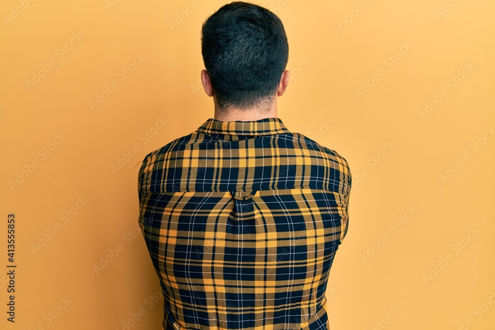 Young hispanic man wearing casual clothes standing backwards looking away with crossed arms Young hispanic man wearing casual clothes standing backwards looking away with crossed arms