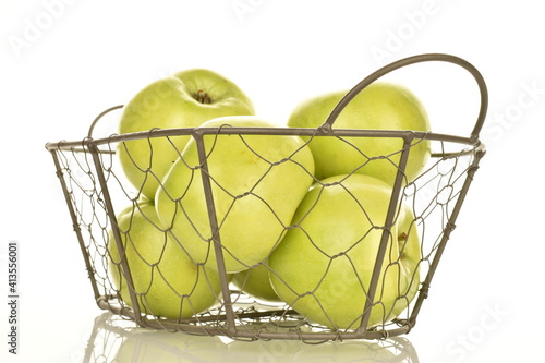 Several sweet green apples by Renet Simirenko with a basket, close-up, isolated on white. photo