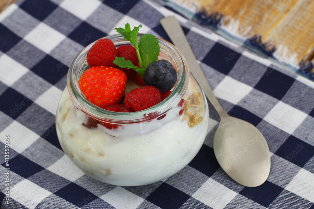 Perfect breakfast: bio yoghurt with granola, fresh strawberries, raspberries and blueberries in transparent glass