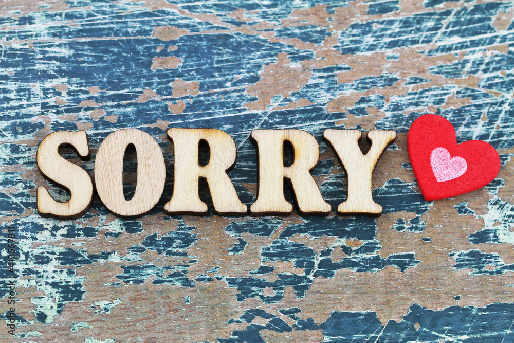 Sorry written with wooden letters on rustic surface with red heart