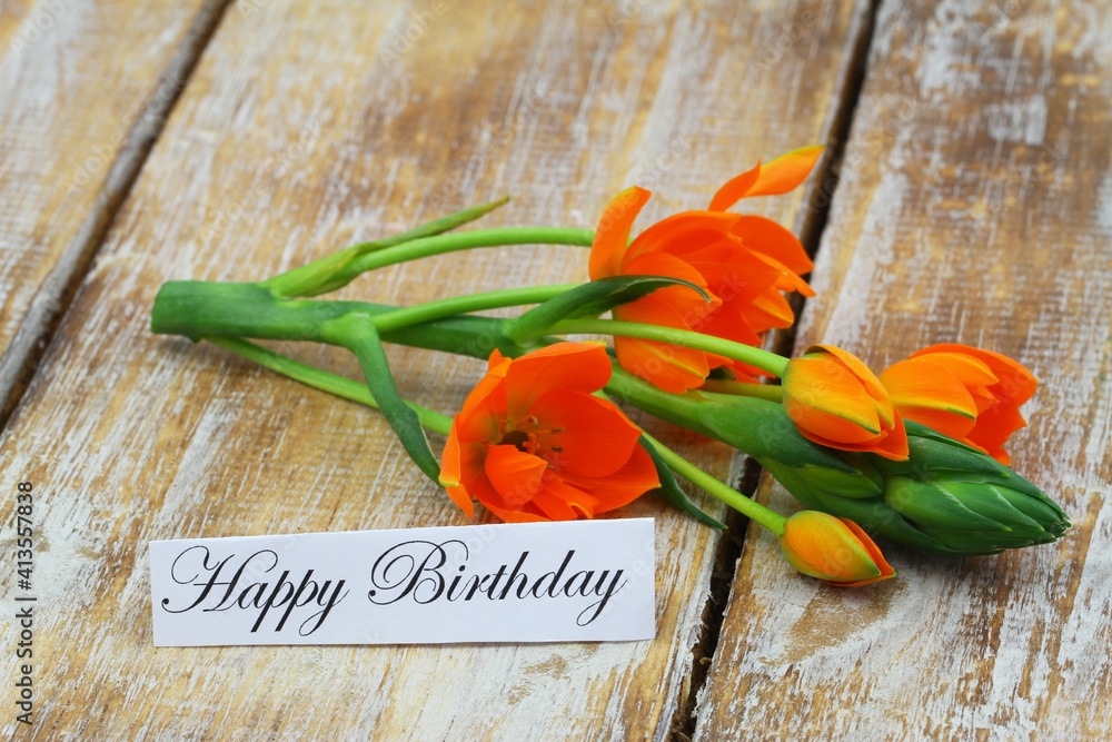 Happy Birthday card with orange flowers on wooden surface