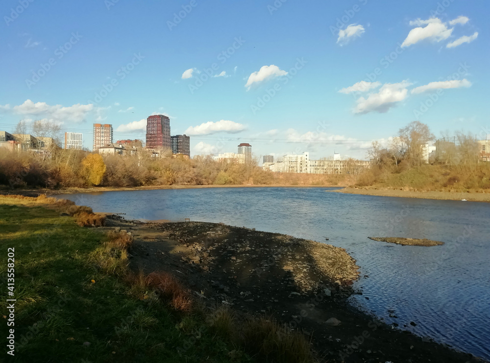 Autumn landscape and river Iset. Cityscape, view to the city of Yekaterinburg, Russia. Autumn forest within the city limits.