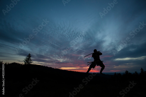 Silhouette of a Japanesesamurai with sword training during sunset