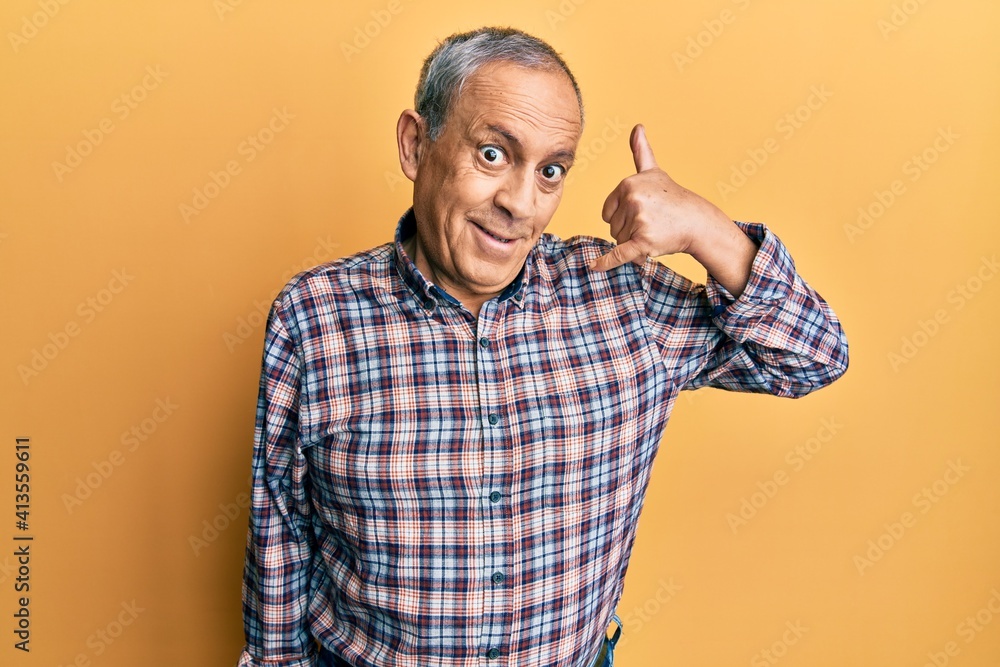 Naklejka premium Handsome senior man with grey hair wearing casual shirt smiling doing phone gesture with hand and fingers like talking on the telephone. communicating concepts.