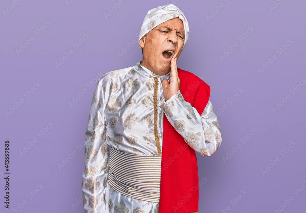 Senior hispanic man wearing tradition sherwani saree clothes touching mouth with hand with painful expression because of toothache or dental illness on teeth. dentist Senior hispanic man wearing tradition sherwani saree clothes touching mouth with hand with painful expression because of toothache or dental illness on teeth. dentist