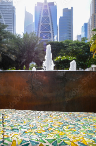 Fontaine moderne en cuivre ou métal dans un parc de quartier résidentiel à Dubaï avec les gratte-ciel en arrière-plan.