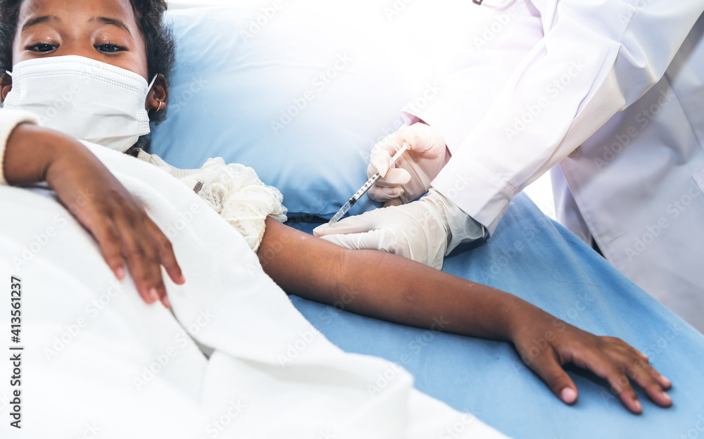Obraz premium The doctor is vaccinating Prevent Covid-19 or Coronavirus for 5-year- old girl is mixed race African, who wearing a surgical masks Lying in patient bed, to vaccine and health care concept.