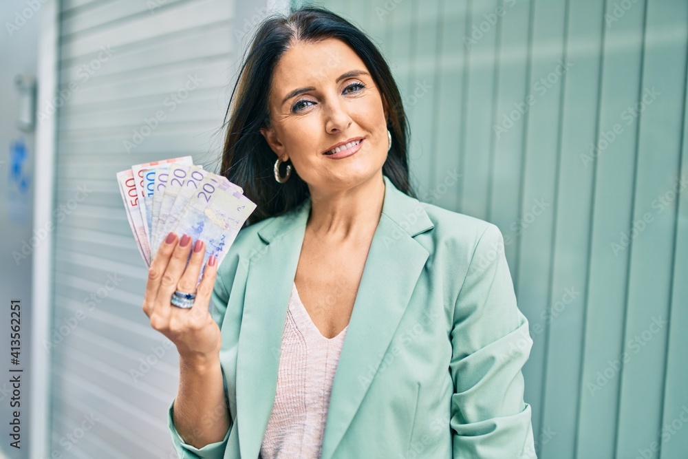 Confident business woman wearing elegant suit standing at the street holding swedish krona banknotes Confident business woman wearing elegant suit standing at the street holding swedish krona banknotes