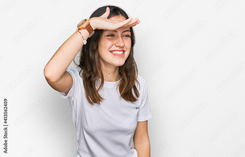 Young beautiful woman wearing casual white t shirt very happy and smiling looking far away with hand over head. searching concept.