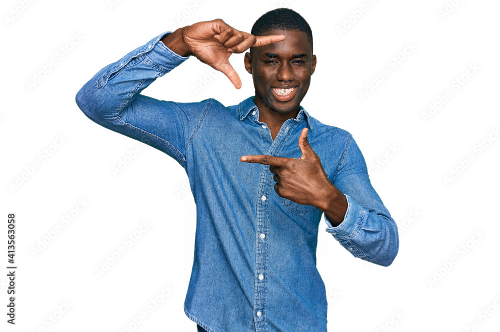 Young african american man wearing casual clothes smiling making frame with hands and fingers with happy face. creativity and photography concept. Young african american man wearing casual clothes smiling making frame with hands and fingers with happy face. creativity and photography concept.