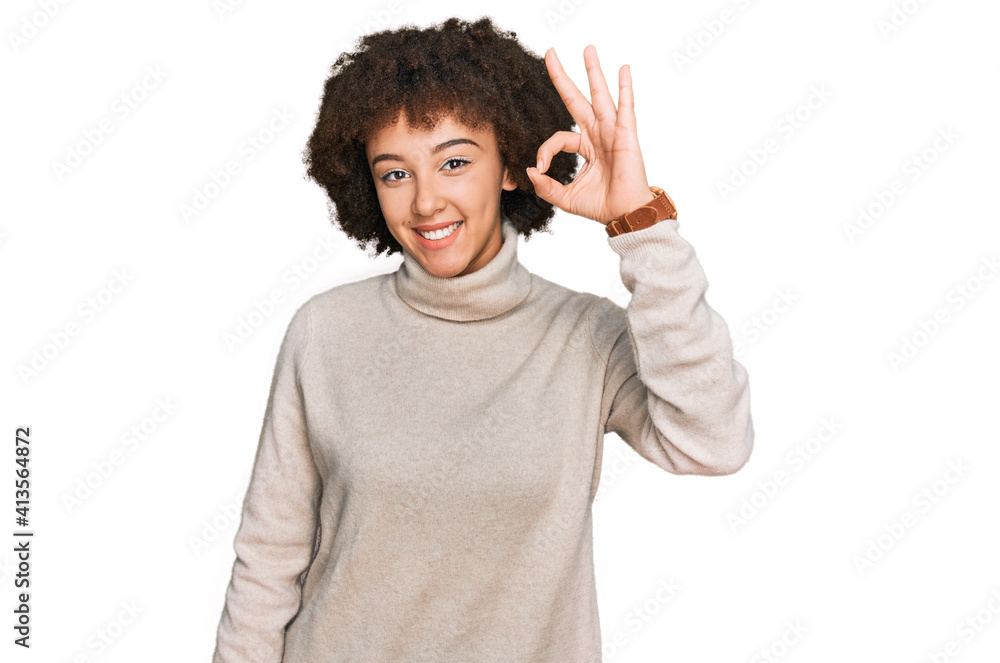 Young hispanic girl wearing wool winter sweater smiling positive doing ok sign with hand and fingers. successful expression. Young hispanic girl wearing wool winter sweater smiling positive doing ok sign with hand and fingers. successful expression.
