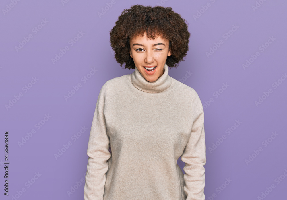 Young hispanic girl wearing wool winter sweater winking looking at the camera with sexy expression, cheerful and happy face. Young hispanic girl wearing wool winter sweater winking looking at the camera with sexy expression, cheerful and happy face.