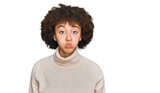 Young hispanic girl wearing wool winter sweater puffing cheeks with funny face. mouth inflated with air, crazy expression.
