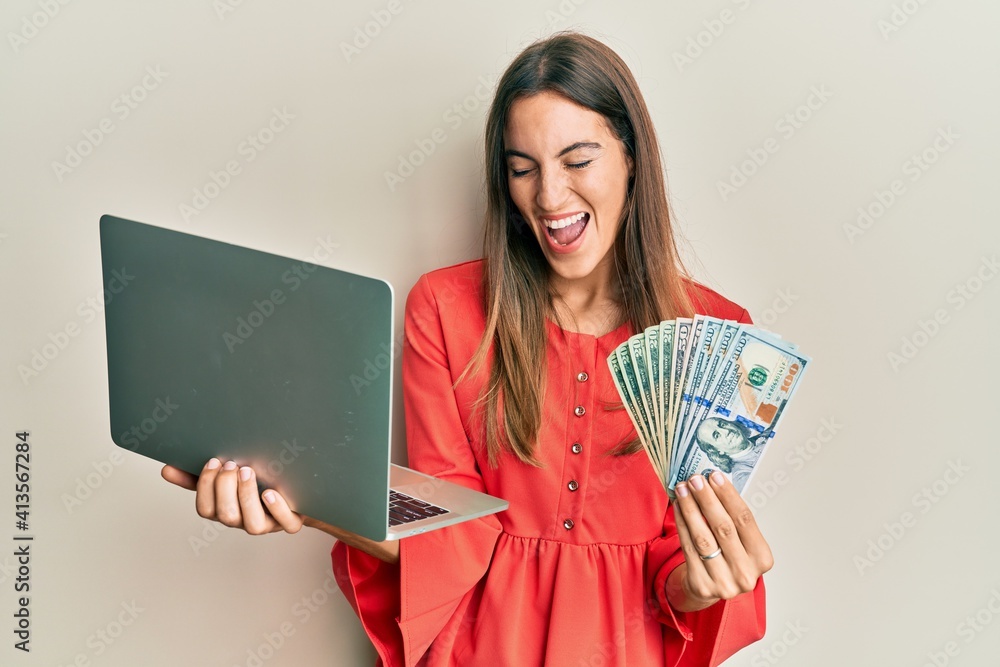 Young beautiful woman working at the office holding dollars smiling and laughing hard out loud because funny crazy joke.