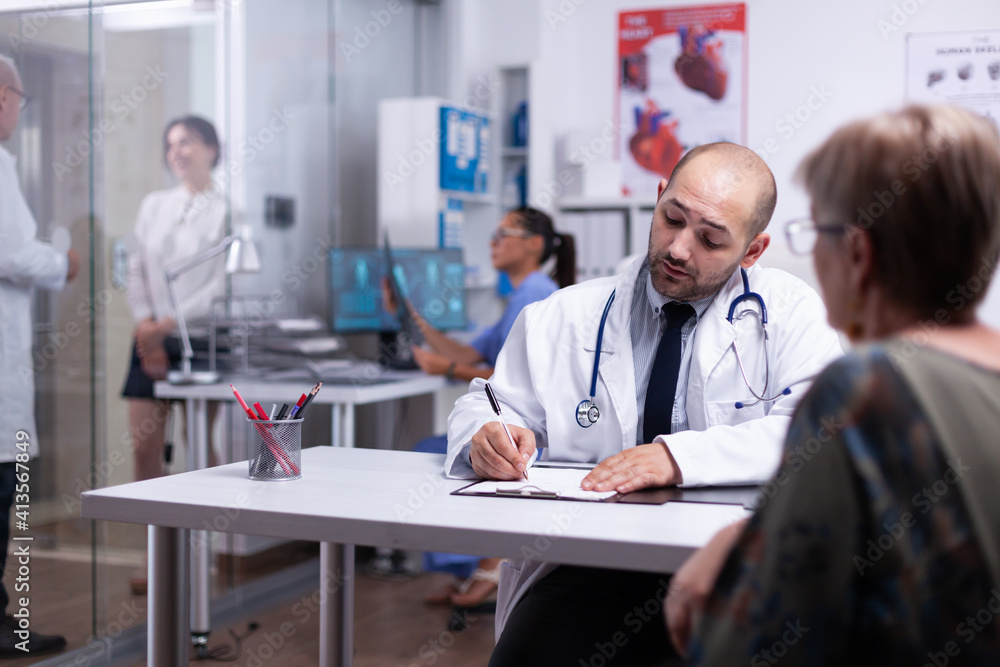 Obraz premium Specialist doctor prescribing treatment for senior woman writting on clipboard. Older patient visiting physician telling about health complaints, medical practitioner asking questions talking about
