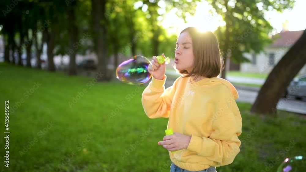 Pretty teenage girl blowing soap bubbles on a sunset. Child having fun in a park in summer. Funny activities for kids. Pretty teenage girl blowing soap bubbles on a sunset. Child having fun in a park in summer. Funny activities for kids.