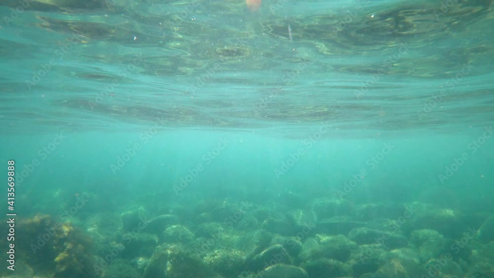 Waves underwater with sun rays. Transparent water with surface in ocean Waves underwater with sun rays. Transparent water with surface in ocean