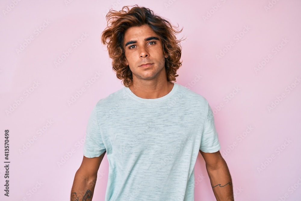 Young hispanic man wearing casual clothes relaxed with serious expression on face. simple and natural looking at the camera. Young hispanic man wearing casual clothes relaxed with serious expression on face. simple and natural looking at the camera.