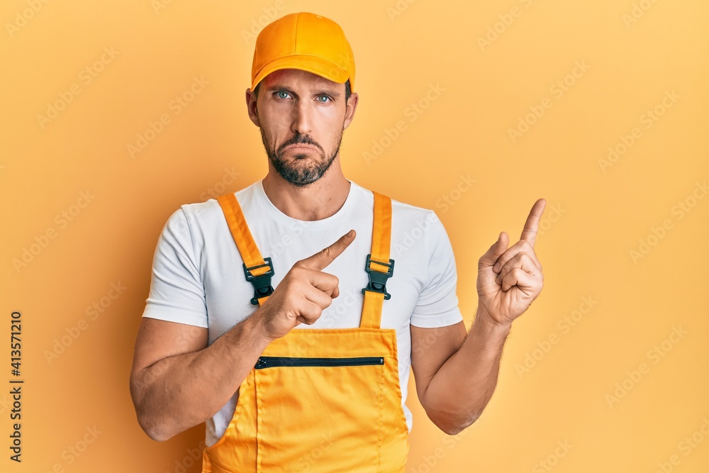 Young handsome man wearing handyman uniform pointing to the side depressed and worry for distress, crying angry and afraid. sad expression.