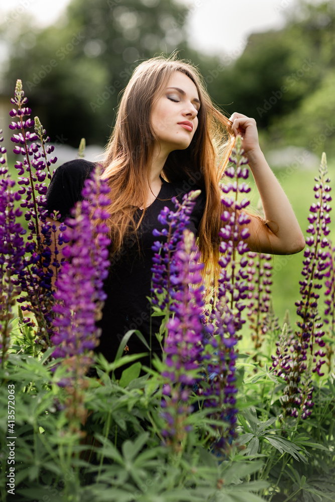beautiful young girl with long hair stands in a fashion pose among purple flowers beautiful young girl with long hair stands in a fashion pose among purple flowers