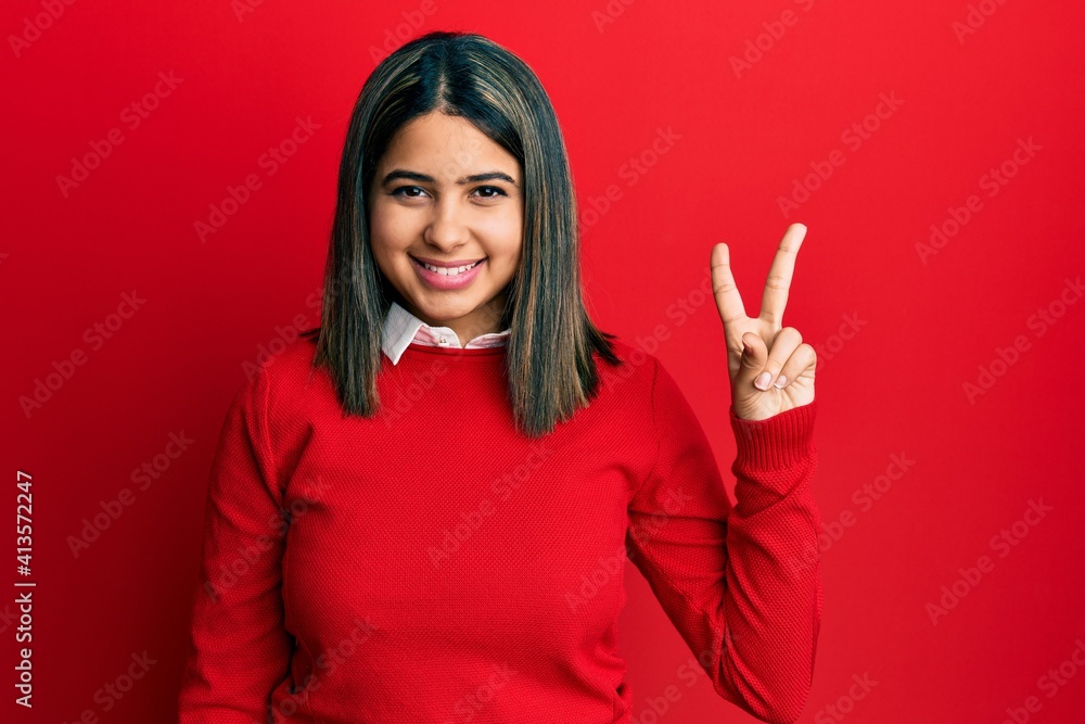 Young latin woman wearing casual clothes showing and pointing up with fingers number two while smiling confident and happy. Young latin woman wearing casual clothes showing and pointing up with fingers number two while smiling confident and happy.