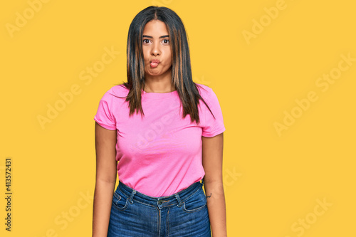 Young latin girl wearing casual clothes making fish face with lips, crazy and comical gesture. funny expression.