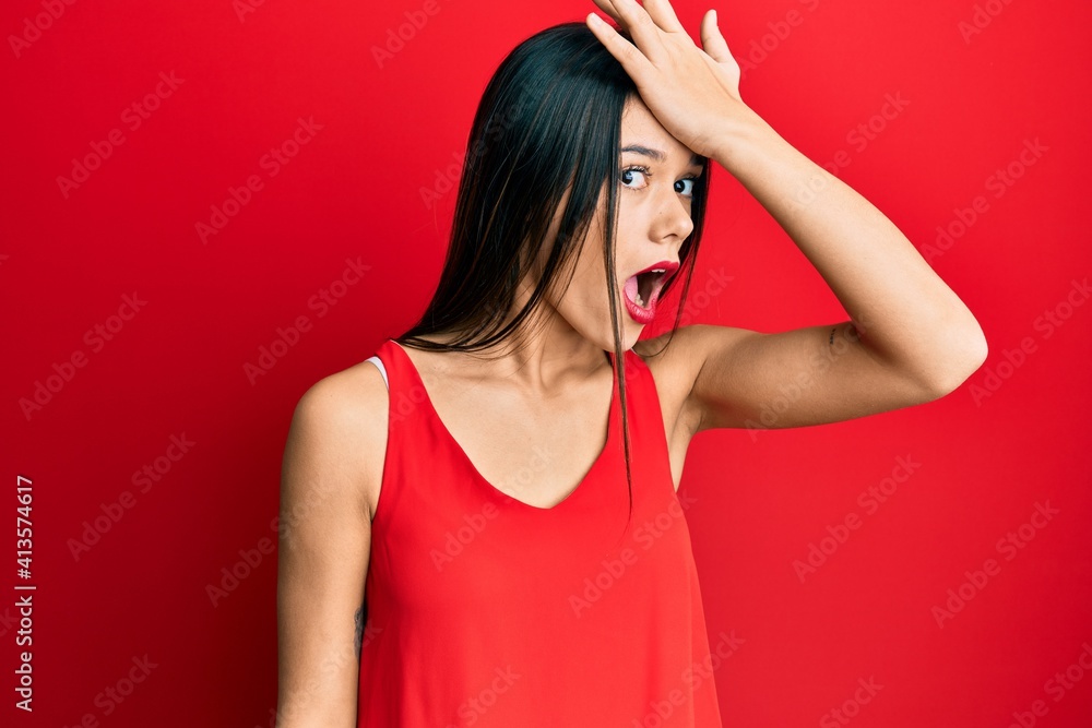 Young hispanic girl wearing casual style with sleeveless shirt surprised with hand on head for mistake, remember error. forgot, bad memory concept. Young hispanic girl wearing casual style with sleeveless shirt surprised with hand on head for mistake, remember error. forgot, bad memory concept.