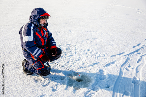 A fisherman is fishing with a winter spinning rod on a frozen lake