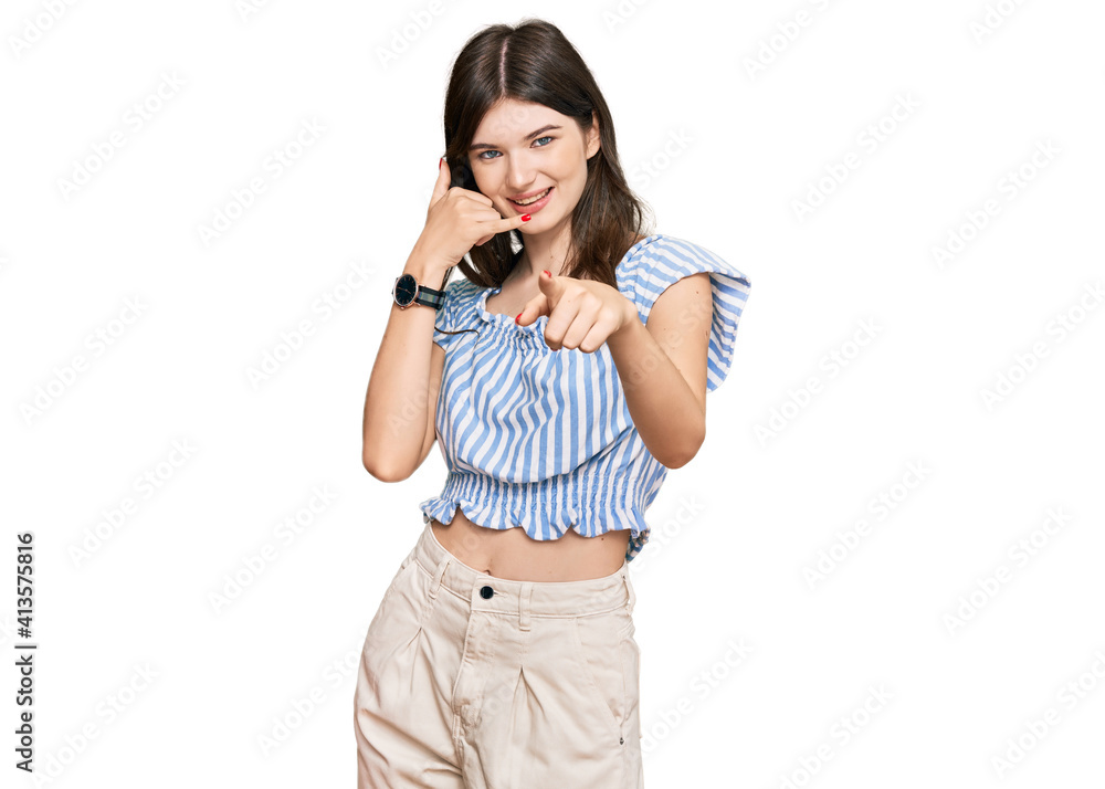 Young beautiful caucasian girl wearing casual clothes smiling doing talking on the telephone gesture and pointing to you. call me. Young beautiful caucasian girl wearing casual clothes smiling doing talking on the telephone gesture and pointing to you. call me.