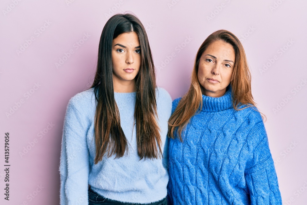 Hispanic family of mother and daughter wearing wool winter sweater relaxed with serious expression on face. simple and natural looking at the camera. Hispanic family of mother and daughter wearing wool winter sweater relaxed with serious expression on face. simple and natural looking at the camera.