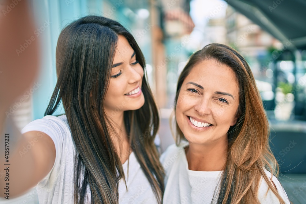 Beautiful hispanic mother and daughter smiling happy making selfie by the camera at the city. Beautiful hispanic mother and daughter smiling happy making selfie by the camera at the city.