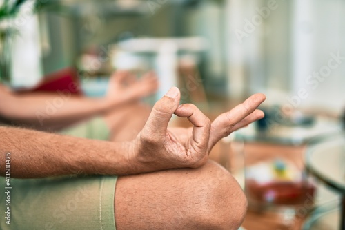 Middle age handsome caucasian man relaxing at sitting on the sofa meditating at home