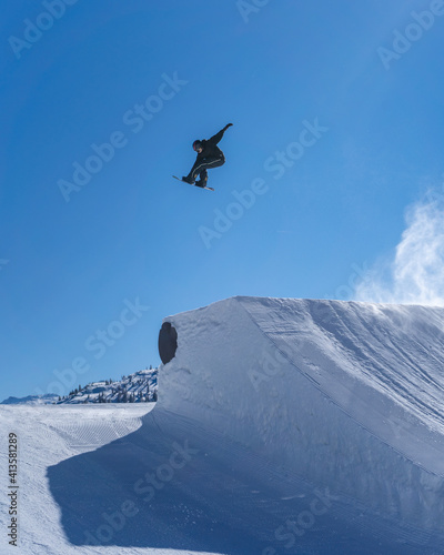 Snowboarder performing an inverted trick in a snowpark in Austria on a sunny day