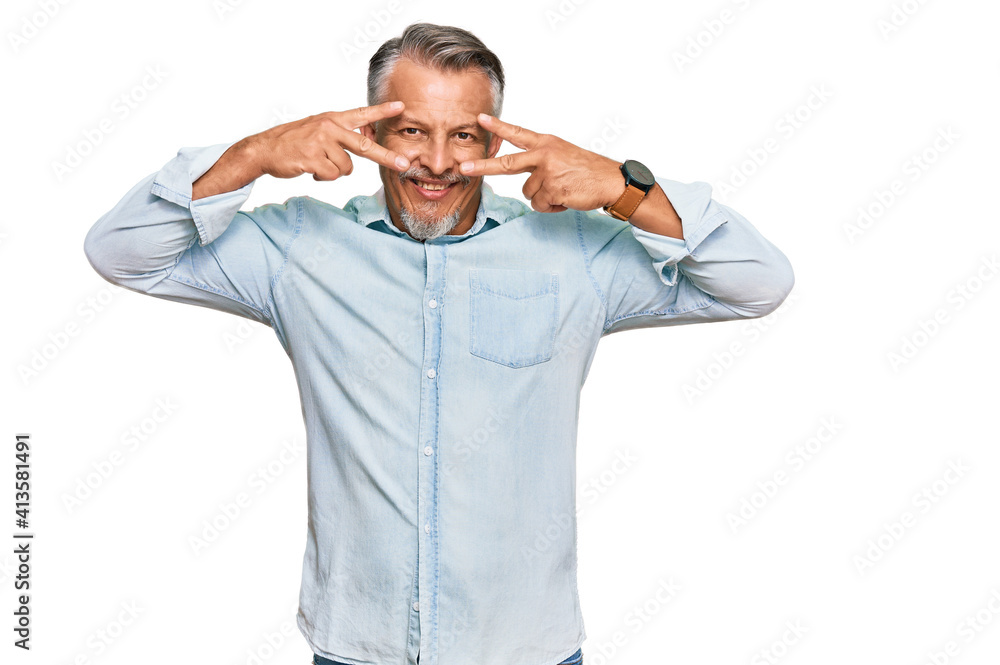 Middle age grey-haired man wearing casual clothes doing peace symbol with fingers over face, smiling cheerful showing victory Middle age grey-haired man wearing casual clothes doing peace symbol with fingers over face, smiling cheerful showing victory