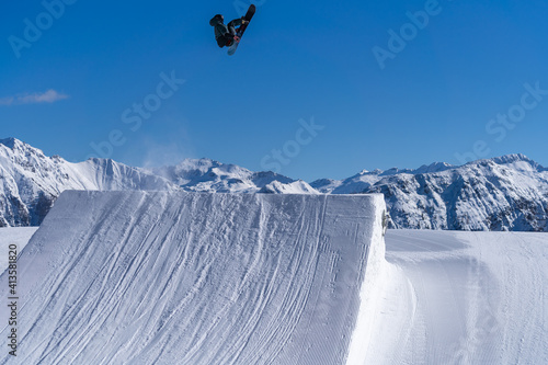 Snowboarder performing an inverted trick in a snowpark in Austria on a sunny day