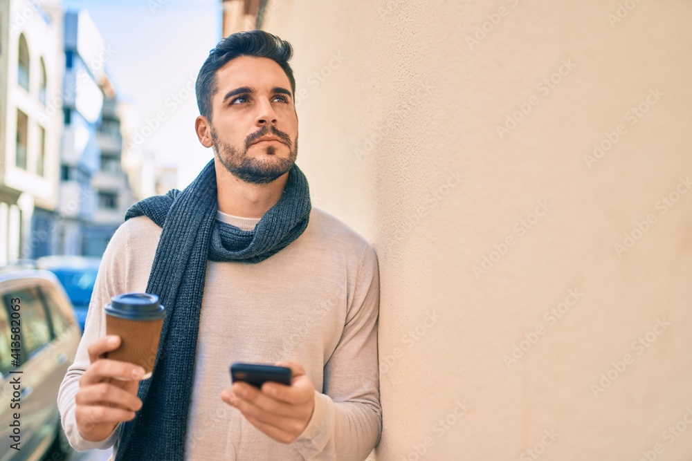 Young hispanic man with serious expression using smartphone and drinking take away coffee at the city. Young hispanic man with serious expression using smartphone and drinking take away coffee at the city.