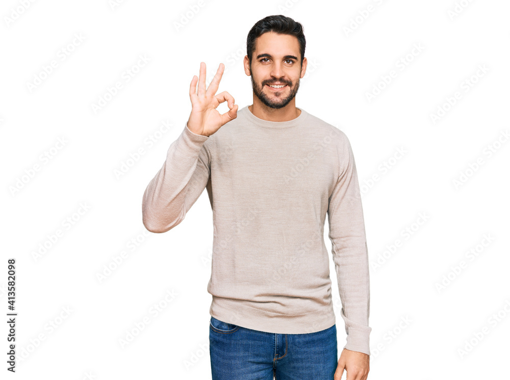 Fototapeta premium Young hispanic man wearing casual clothes smiling positive doing ok sign with hand and fingers. successful expression.