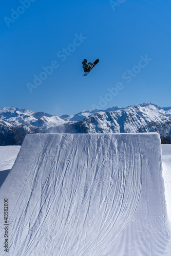 Snowboarder performing an inverted trick in a snowpark in Austria on a sunny day