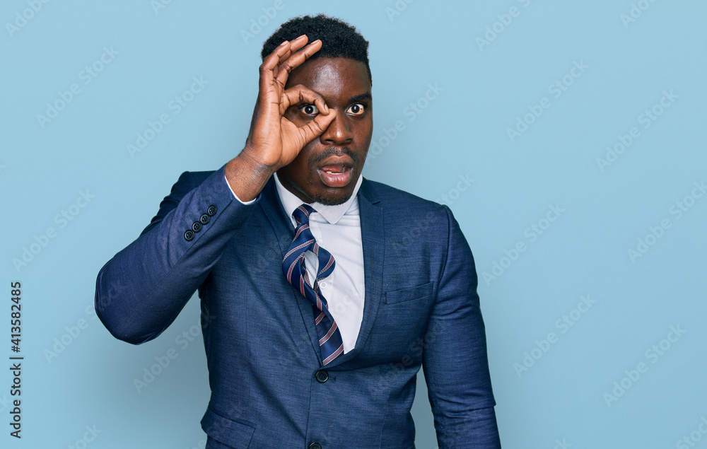 Handsome business black man wearing business suit and tie doing ok gesture shocked with surprised face, eye looking through fingers. unbelieving expression. Handsome business black man wearing business suit and tie doing ok gesture shocked with surprised face, eye looking through fingers. unbelieving expression.