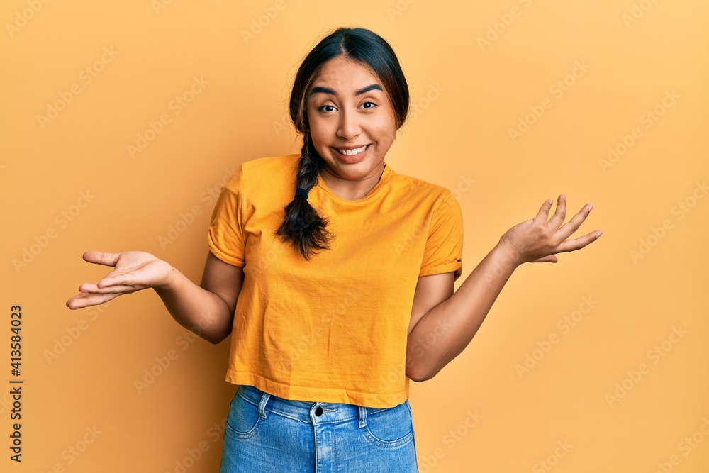 Young latin woman wearing casual clothes clueless and confused expression with arms and hands raised. doubt concept. Young latin woman wearing casual clothes clueless and confused expression with arms and hands raised. doubt concept.