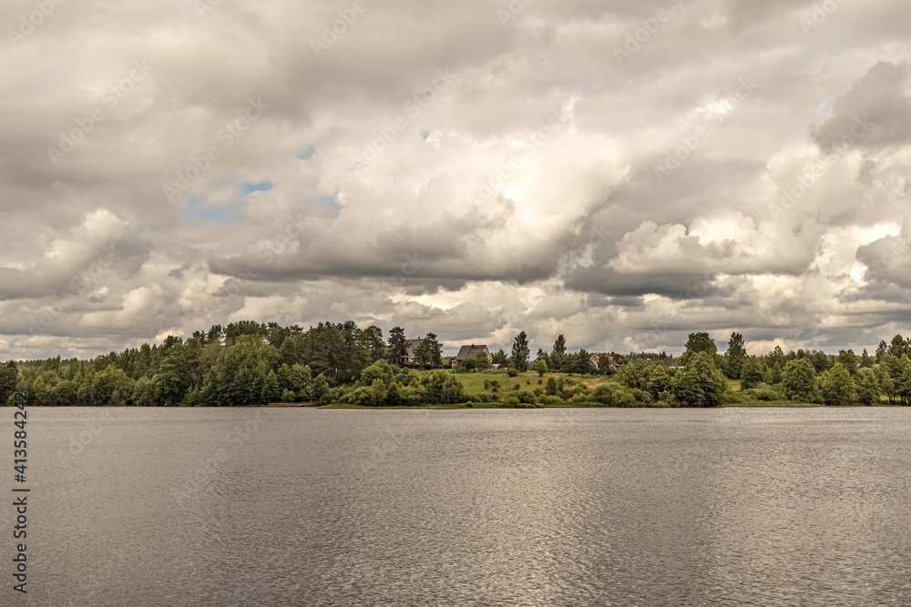 Cottage village on the shore of the lake at sunset before the rain. The clouds are thunderous in the sky. Landscape