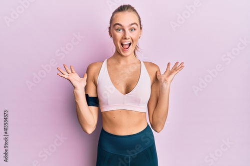 Beautiful blonde woman wearing sportswear and arm band celebrating crazy and amazed for success with arms raised and open eyes screaming excited. winner concept © Krakenimages.com