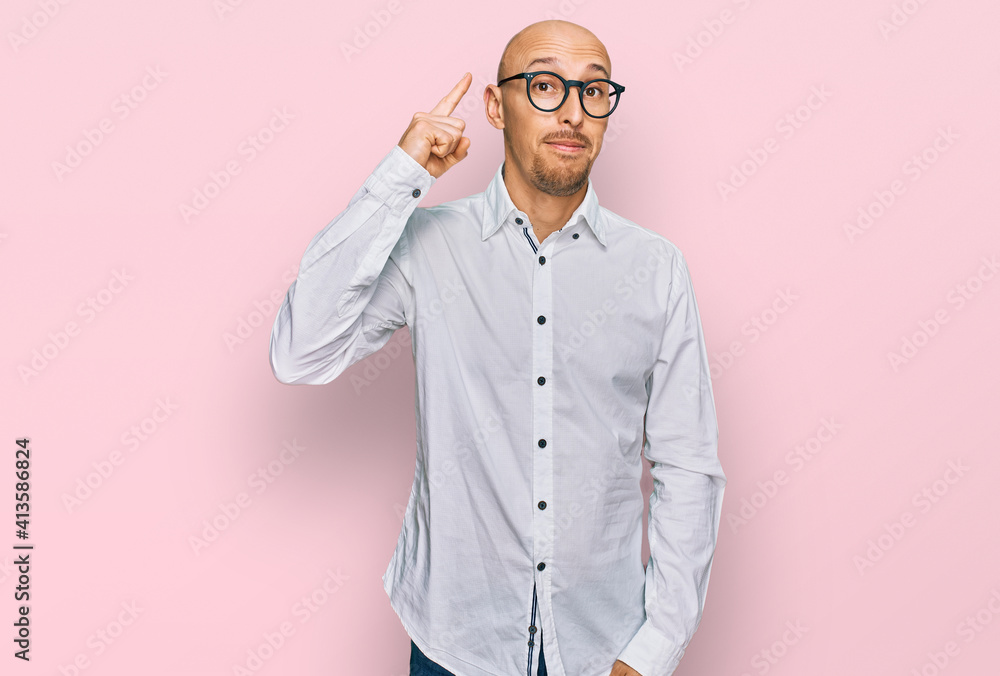 Bald man with beard wearing business shirt and glasses pointing finger up with successful idea. exited and happy. number one. Bald man with beard wearing business shirt and glasses pointing finger up with successful idea. exited and happy. number one.