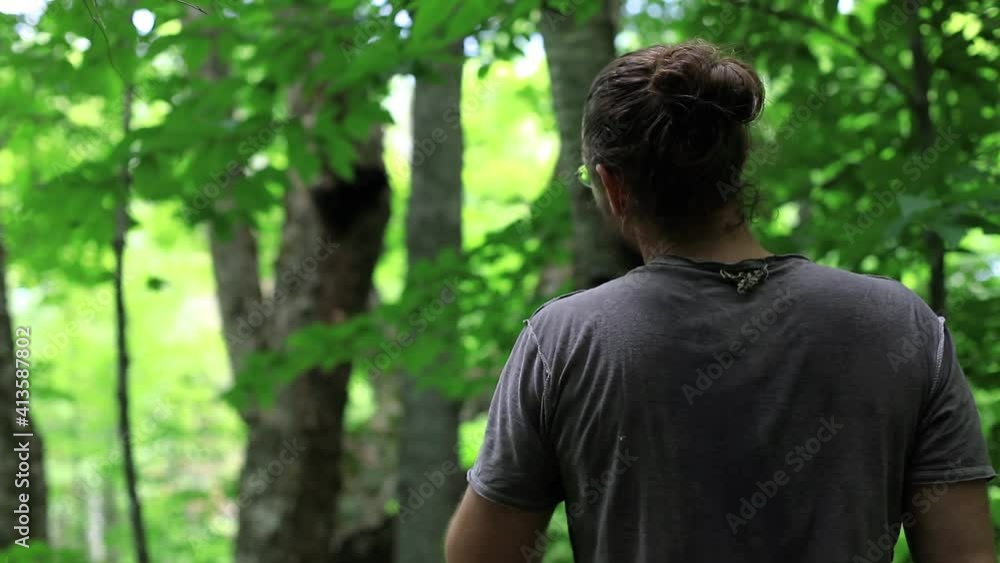 Selective focus. In the foreground, a man is pointing towards a tree in the distance, in the blurred background. Green natural light filtering from the trees. Selective focus. In the foreground, a man is pointing towards a tree in the distance, in the blurred background. Green natural light filtering from the trees.
