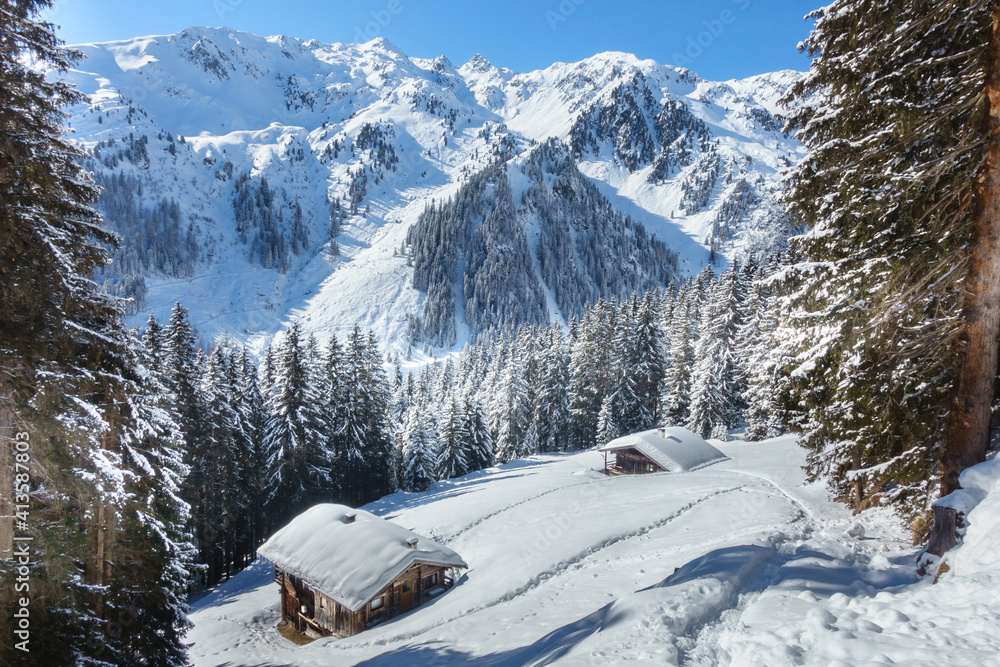 Fototapeta premium Winterlandschaft in den Bergen mit Skihütte und Almhütte