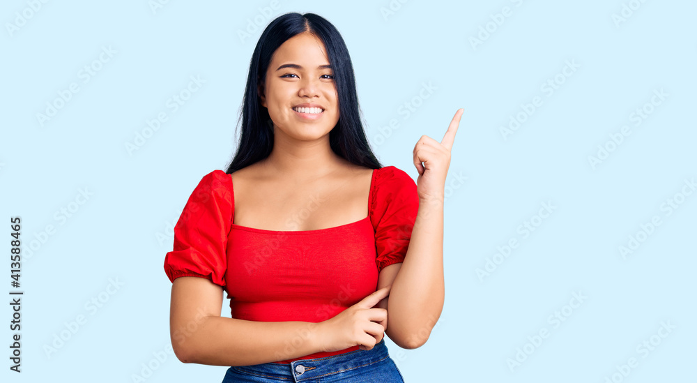 Young beautiful asian girl wearing casual clothes with a big smile on face, pointing with hand and finger to the side looking at the camera. Young beautiful asian girl wearing casual clothes with a big smile on face, pointing with hand and finger to the side looking at the camera.