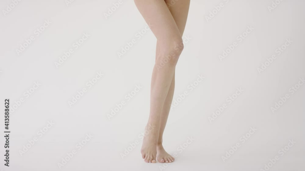 Women's legs close up on a white background. Concept of skin care, cosmetology, cosmetics Women's legs close up on a white background. Concept of skin care, cosmetology, cosmetics