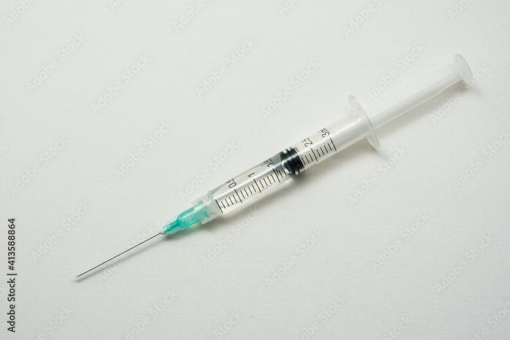 One syringe with liquid on a white surface One syringe with liquid on a white surface
