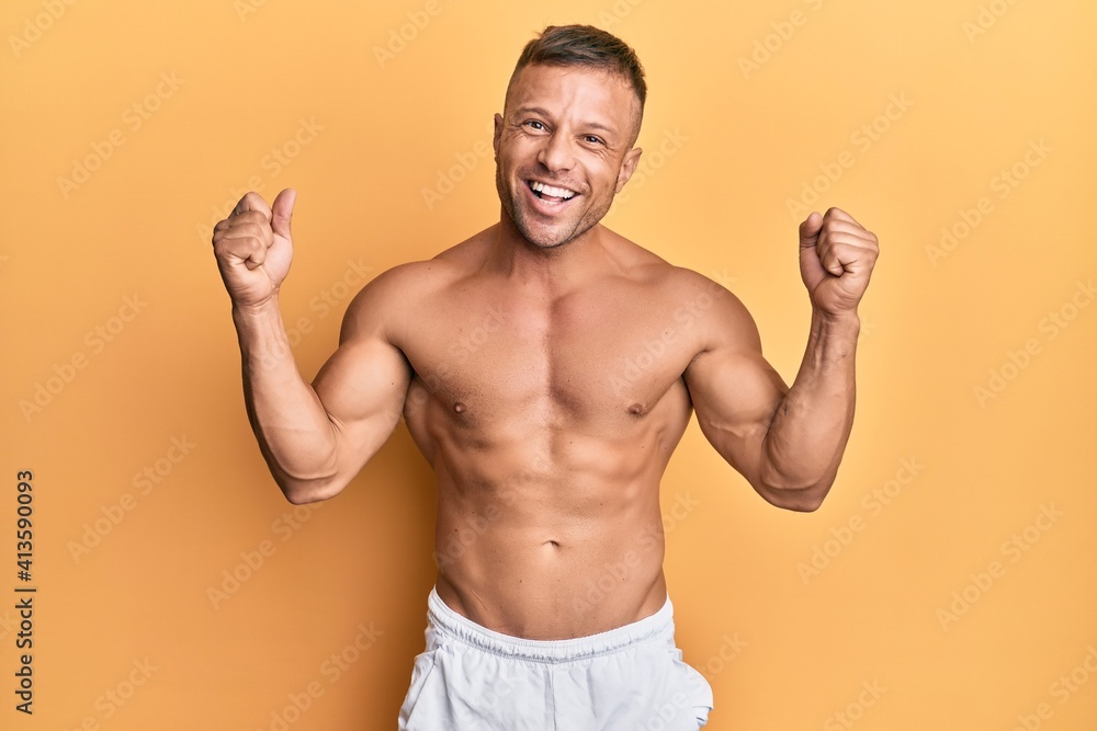 Handsome muscle man standing shirtless screaming proud, celebrating victory and success very excited with raised arms
