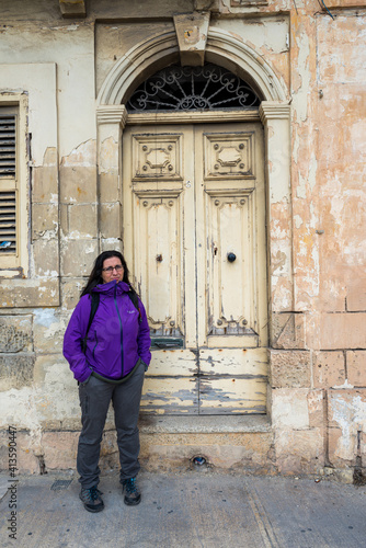 Woman with purple jacket and long hair next to a white door